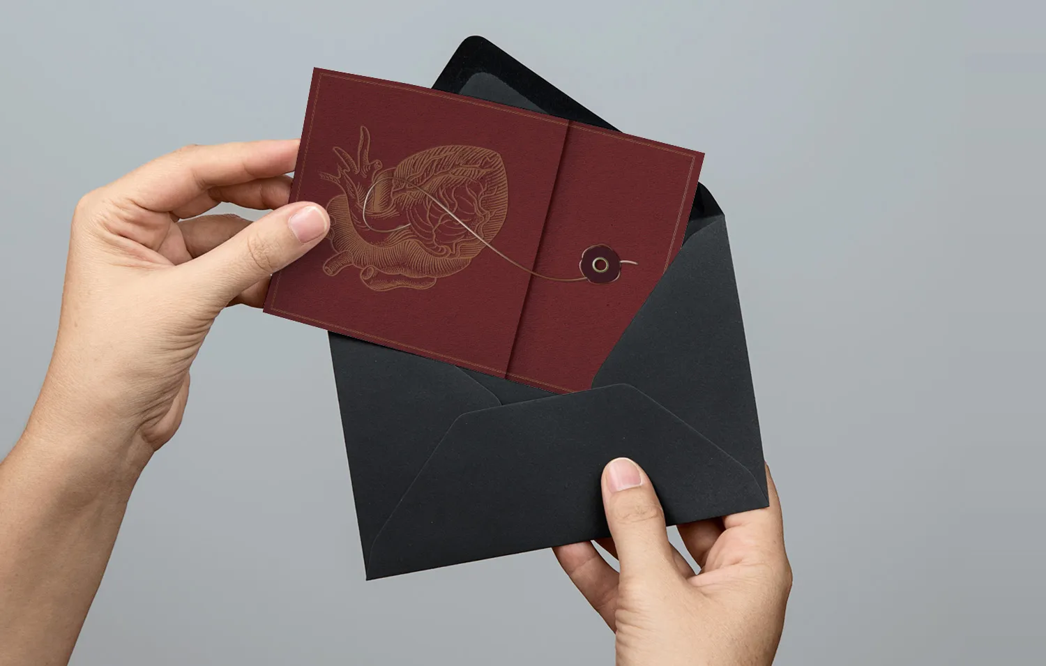 Hands holding an embossed maroon Alvarado Hospital event invitation and its envelope