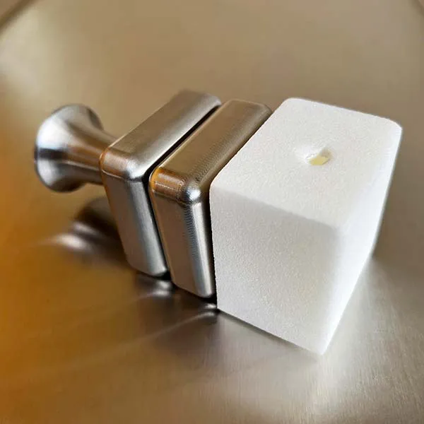 The stainless HypoHolder base with a HypoFoam block seated on its pegs, photographed on a steel surface