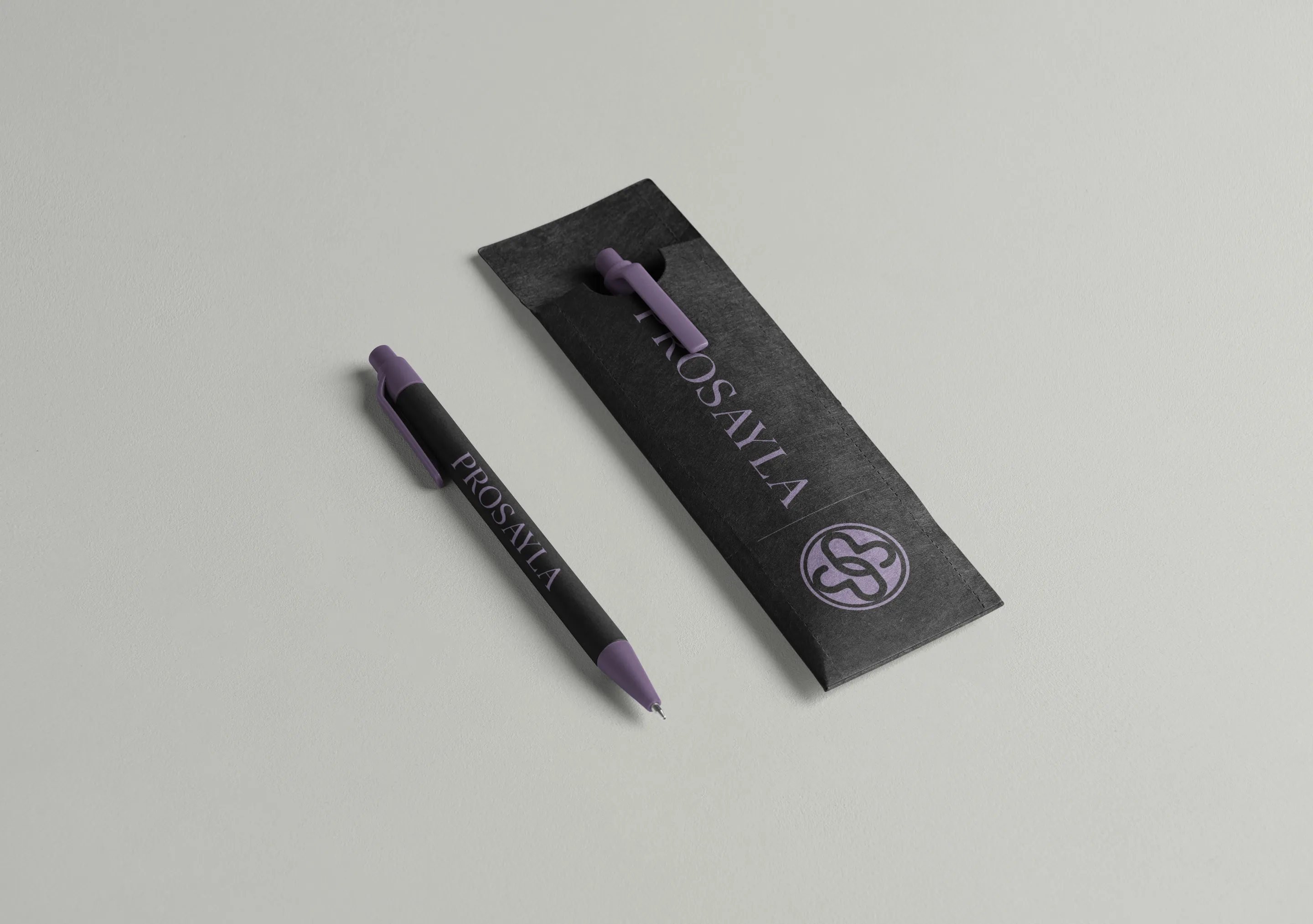 A Prosayla pen and paper pen sleeve, the wordmark and mark printed in lavender on black