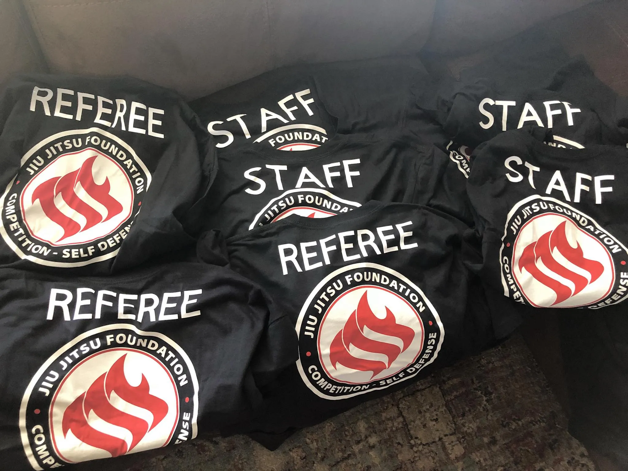 Staff and referee shirts stacked, each carrying the circular academy patch