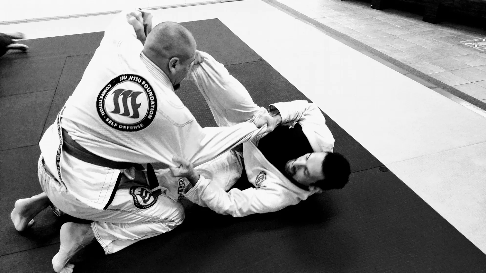Two members training in patched gis, photographed in black and white