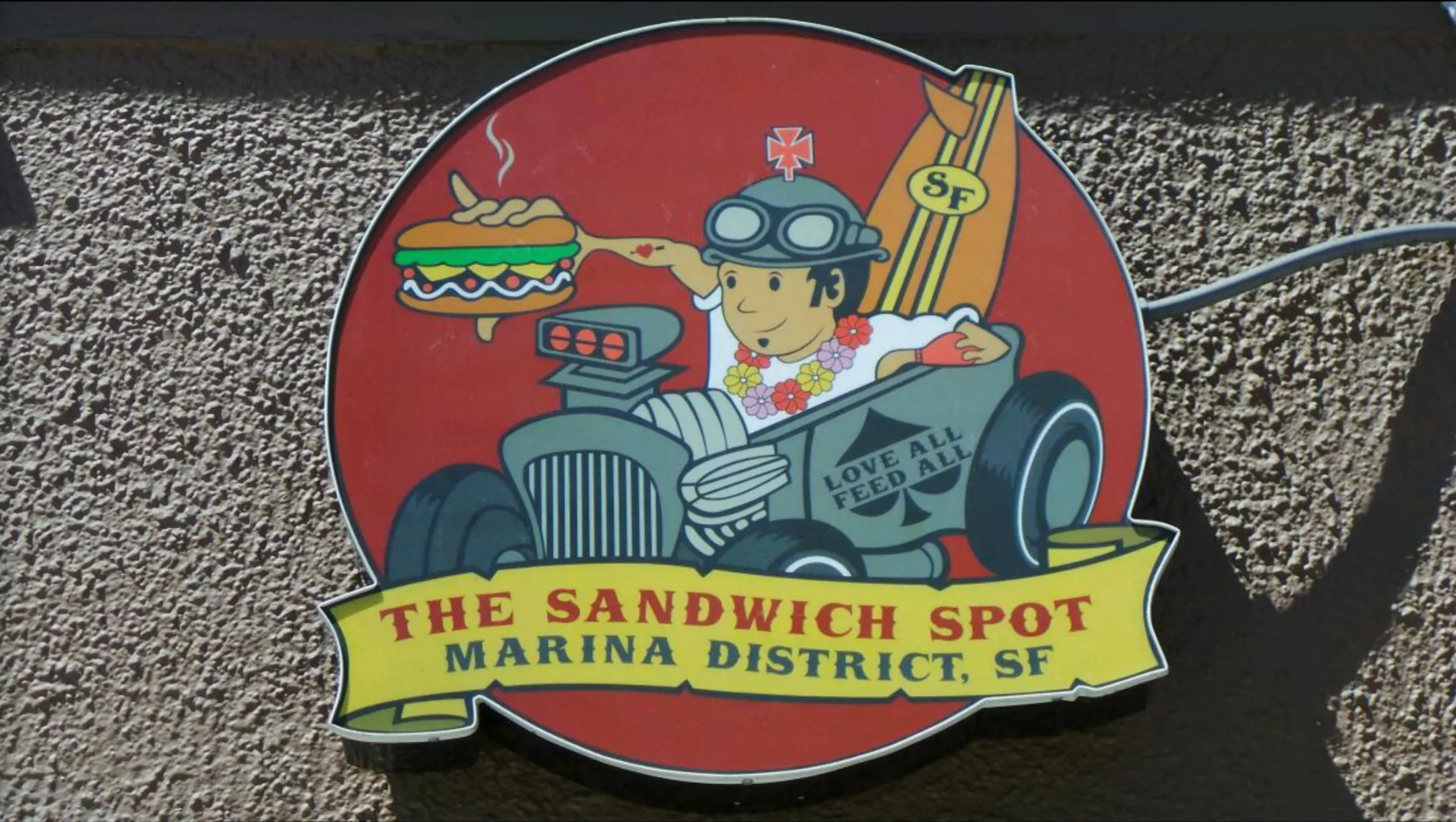 The dimensional exterior sign in close view, the illustrated mark cut and mounted on stucco