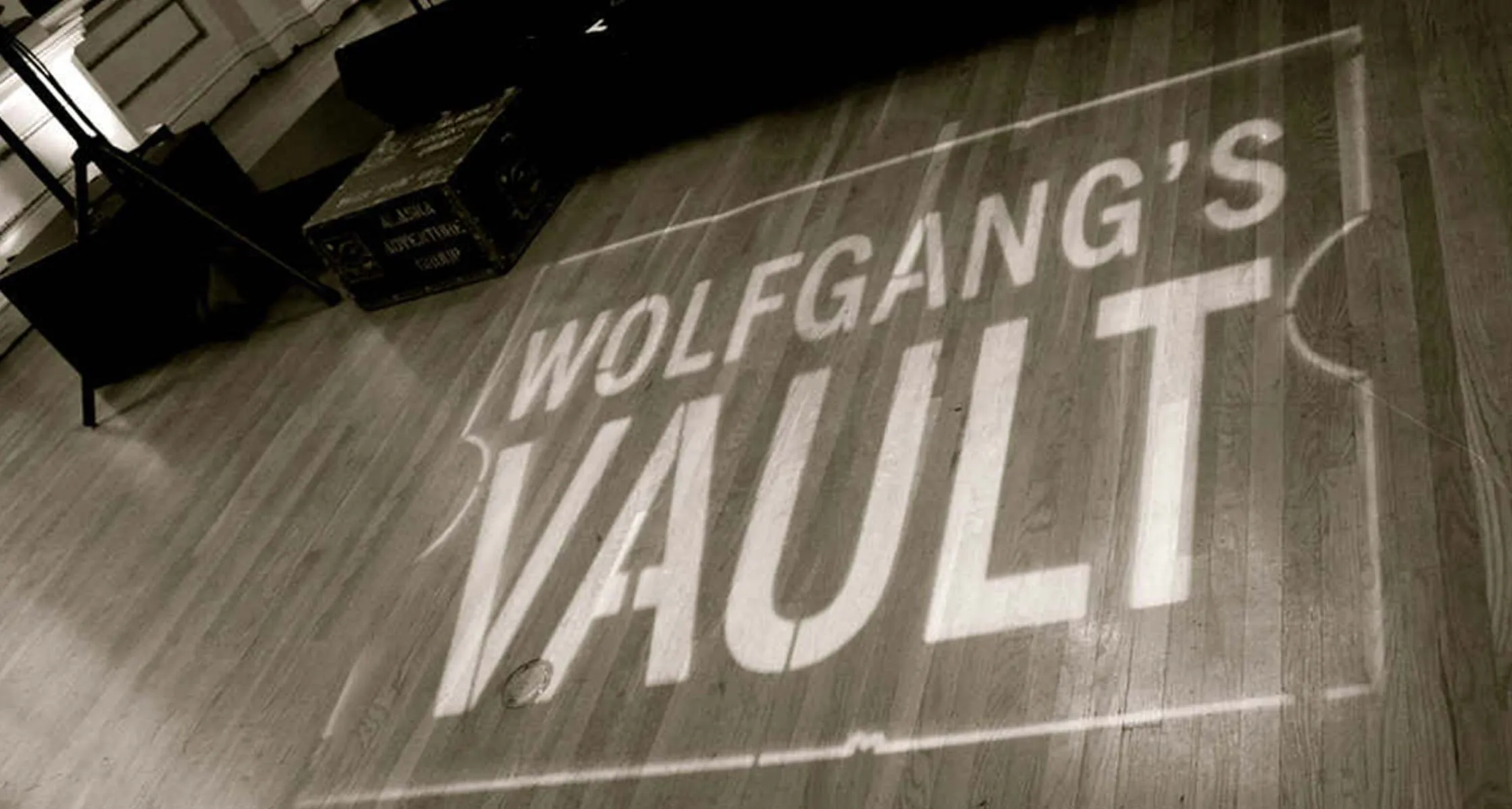 The Wolfgang’s Vault logo projected across a wooden venue floor beside stage equipment