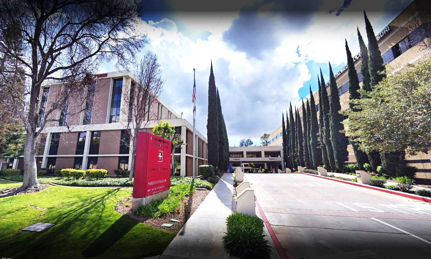 The Alvarado Hospital campus entrance drive, with a vertical hospital banner mounted at the roadside and the main building beyond