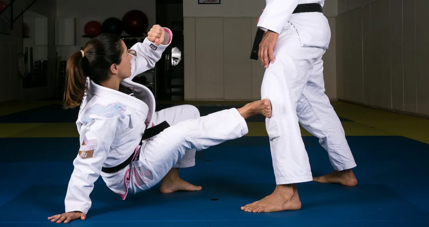 Two members of the Jiu Jitsu Foundation academy training in branded gis on the mats, a mirrored training room with equipment behind them